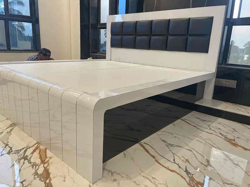 Bed with a white marble-finish frame and black upholstered headboard on a marble floor