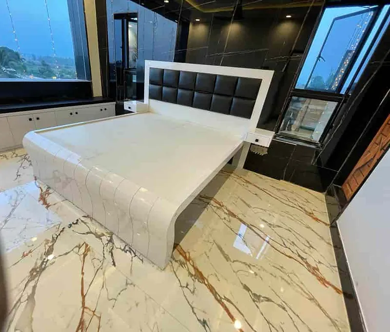 Bed with an upholstered headboard beside large windows
