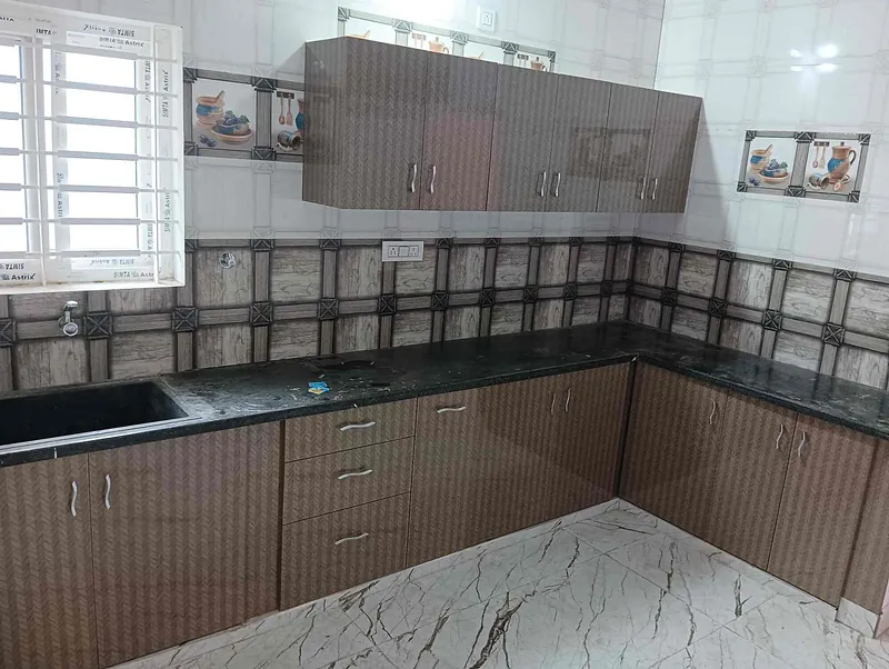 L-shaped modular kitchen with a black granite worktop and textured brown cabinets